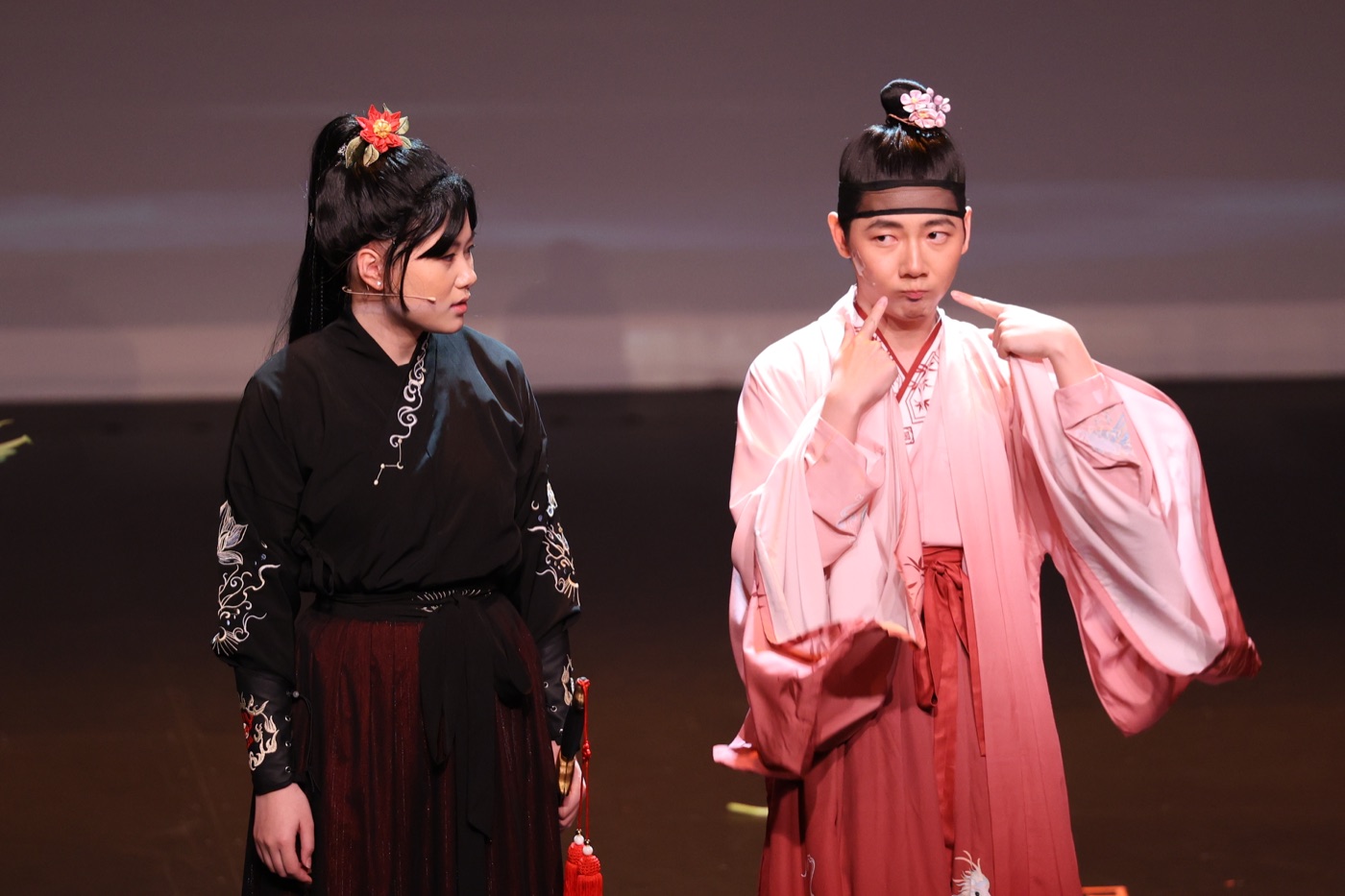 Hua makes a comic expression beside another performer in period costume.