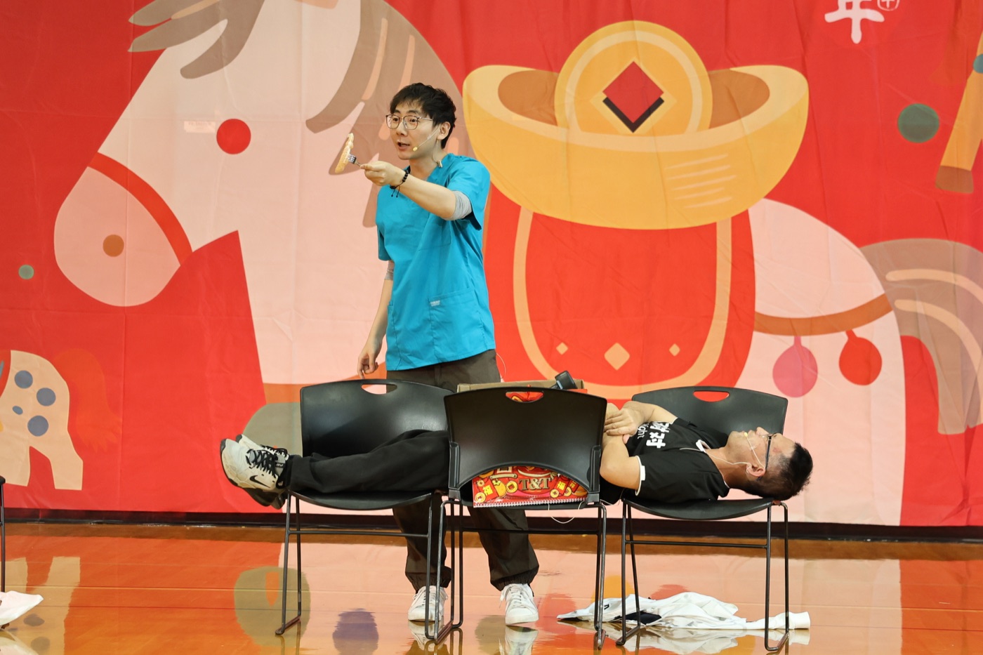 Hua performs the surgery sketch against a vivid red New Year backdrop.