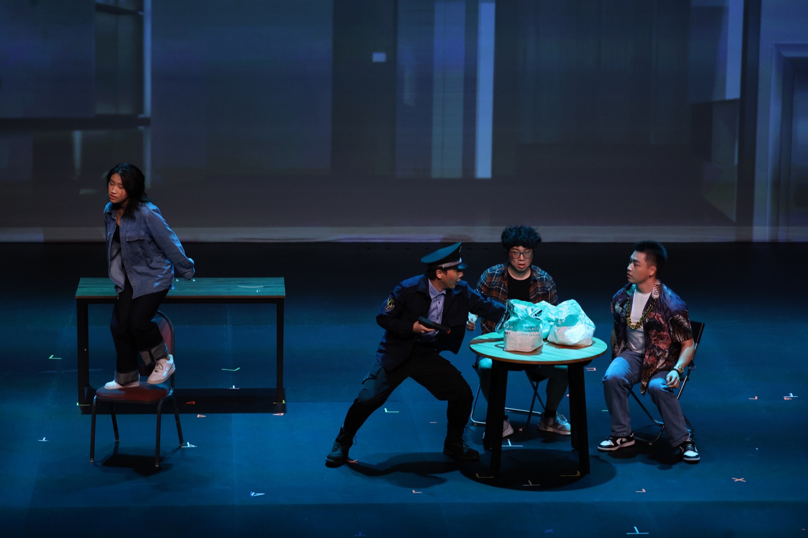 The Crazy Delivery ensemble performs around a restaurant table on stage.